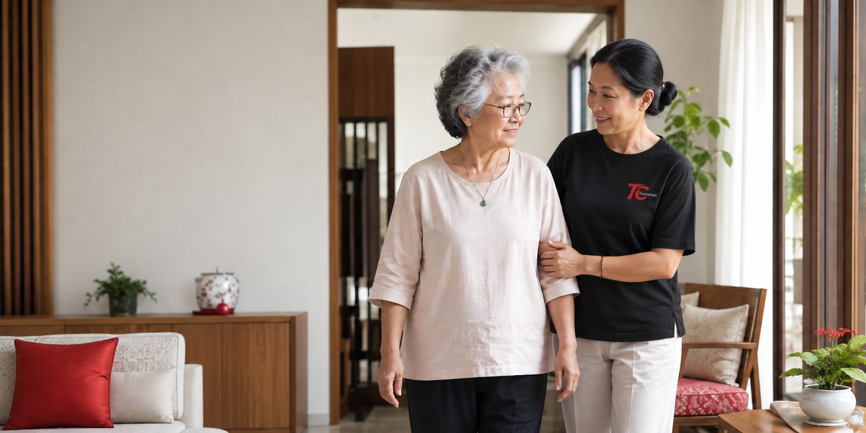 A helper walking arm in arm with an elderly woman through her living room